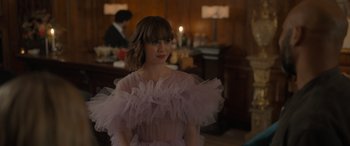 Movie still from “The Bubble” (2022), directed by Judd Apatow – A woman in a pink dress standing in a room; Medium shot, Over the shoulder angle