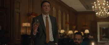 Movie still from “The Bubble” (2022), directed by Judd Apatow – A man in a suit holding a glass of wine; Medium shot, Low angle