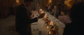 Movie still from “The Bubble” (2022), directed by Judd Apatow – A group of people sitting around a table with candles; Wide shot, High angle