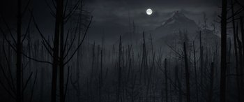 Movie still from “The Bubble” (2022), directed by Judd Apatow – A full moon rises over a forest of dead trees; Extreme Wide shot, High angle