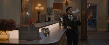 Movie still from “The Bubble” (2022), directed by Judd Apatow – A man in a suit smoking a cigarette at a bar; Medium shot, Low angle