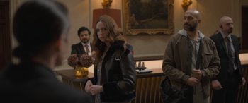 Movie still from “The Bubble” (2022), directed by Judd Apatow – A woman in a leather jacket standing in front of other people; Medium shot, Over the shoulder angle