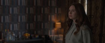 Movie still from “The Bubble” (2022), directed by Judd Apatow – A woman standing in front of bookshelves in a room; Medium shot, Over the shoulder angle