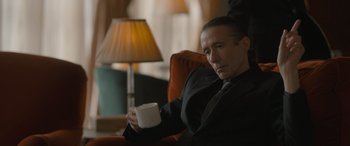 Movie still from “The Bubble” (2022), directed by Judd Apatow – A man sitting in a chair holding a coffee mug; Close Up shot, Low angle