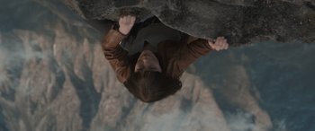 Movie still from “The Bubble” (2022), directed by Judd Apatow – A person hanging on a rock in the air; Medium shot, Overhead angle