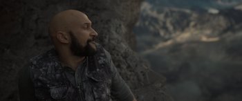 Movie still from “The Bubble” (2022), directed by Judd Apatow – A man with a bald head is standing on a cliff; Close Up shot, Low angle