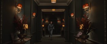 Movie still from “The Bubble” (2022), directed by Judd Apatow – A person running down a hall way in a dark room; Wide shot, High angle