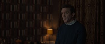 Movie still from “The Bubble” (2022), directed by Judd Apatow – A man standing in front of a book shelf; Medium shot, Over the shoulder angle