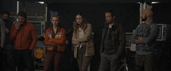 Movie still from “The Bubble” (2022), directed by Judd Apatow – A group of people standing next to each other in a room; Medium shot, Over the shoulder angle