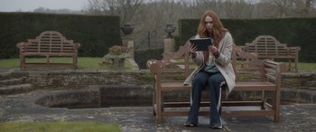 Movie still from “The Bubble” (2022), directed by Judd Apatow – A woman sitting on top of a wooden park bench; Wide shot, Low angle