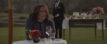 Movie still from “The Bubble” (2022), directed by Judd Apatow – A man sitting at a table with a glass of wine; Medium shot, Over the shoulder angle