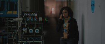 Movie still from “The Bubble” (2022), directed by Judd Apatow – A woman standing in a room talking on a cell phone; Medium shot, Over the shoulder angle