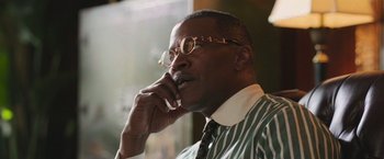 Movie still from “The Burial” (2023), directed by Maggie Betts – An older man wearing glasses talking on a cell phone; Close Up shot, Low angle