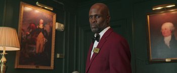 Movie still from “The Burial” (2023), directed by Maggie Betts – A man in a red jacket and a black bow tie; Medium shot, Low angle