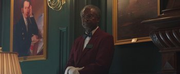 Movie still from “The Burial” (2023), directed by Maggie Betts – A man in a red jacket and white gloves; Medium shot, Low angle