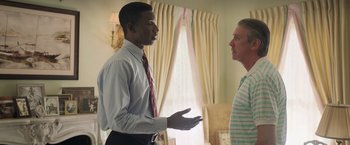 Movie still from “The Burial” (2023), directed by Maggie Betts – A man in a tie talking to another man in a striped shirt; Medium shot, Over the shoulder angle