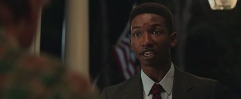 Movie still from “The Burial” (2023), directed by Maggie Betts – A person wearing a suit and tie; Close Up shot, Over the shoulder angle