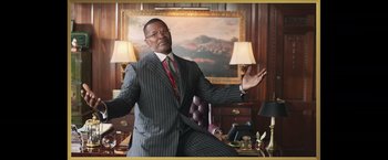 Movie still from “The Burial” (2023), directed by Maggie Betts – A man wearing a suit and tie in a room; Medium shot, Low angle