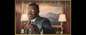 Movie still from “The Burial” (2023), directed by Maggie Betts – A man in a suit and tie pointing at the camera; Medium shot, Low angle