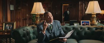 Movie still from “The Burial” (2023), directed by Maggie Betts – A man in a suit and tie holding a book; Medium shot, Low angle