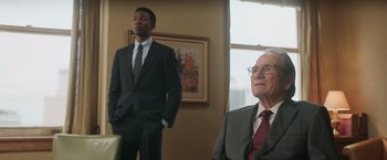 Movie still from “The Burial” (2023), directed by Maggie Betts – A man in a suit standing next to another man in a suit; Medium shot, Low angle