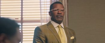 Movie still from “The Burial” (2023), directed by Maggie Betts – A man in a suit and tie wearing glasses; Close Up shot, Low angle