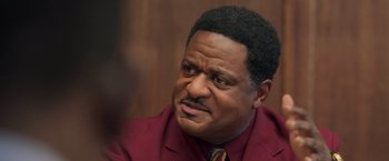 Movie still from “The Burial” (2023), directed by Maggie Betts – A person wearing a suit and tie; Close Up shot, Over the shoulder angle