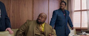 Movie still from “The Burial” (2023), directed by Maggie Betts – A man in a suit and tie next to another man in a suit and tie; Medium shot, Low angle