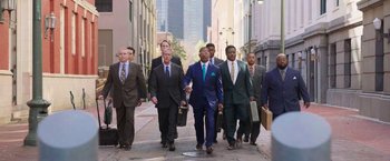 Movie still from “The Burial” (2023), directed by Maggie Betts – A group of men walking down a street holding briefcases; Wide shot, Low angle