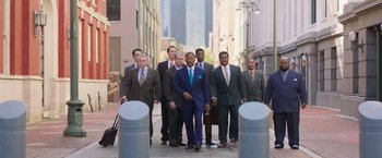 Movie still from “The Burial” (2023), directed by Maggie Betts – A group of men in business suits are walking down the street; Wide shot, Low angle