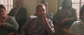 Movie still from “The Burial” (2023), directed by Maggie Betts – A woman sitting in front of other people; Close Up shot, Over the shoulder angle