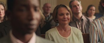 Movie still from “The Burial” (2023), directed by Maggie Betts – An older woman sitting in front of a group of people; Close Up shot, Over the shoulder angle