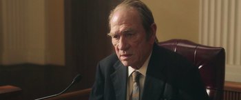 Movie still from “The Burial” (2023), directed by Maggie Betts – An older man wearing a suit and tie; Close Up shot, High angle
