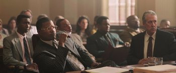 Movie still from “The Burial” (2023), directed by Maggie Betts – A group of people sitting in a room; Medium shot, High angle