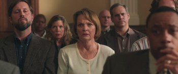 Movie still from “The Burial” (2023), directed by Maggie Betts – A group of people standing in a room; Medium shot, Over the shoulder angle
