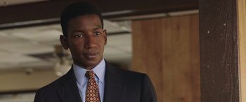 Movie still from “The Burial” (2023), directed by Maggie Betts – A man wearing a suit and tie standing in a room; Close Up shot, Low angle