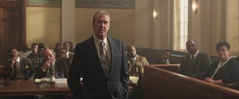 Movie still from “The Burial” (2023), directed by Maggie Betts – A man in a suit standing in front of a judge; Medium shot, Low angle
