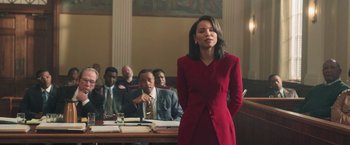 Movie still from “The Burial” (2023), directed by Maggie Betts – A woman in a red dress in front of other people; Medium shot, Low angle