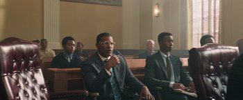 Movie still from “The Burial” (2023), directed by Maggie Betts – A group of men in suits sitting in a court room; Medium shot, Low angle