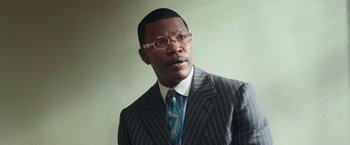 Movie still from “The Burial” (2023), directed by Maggie Betts – A man in a suit and tie wearing glasses; Close Up shot, Low angle