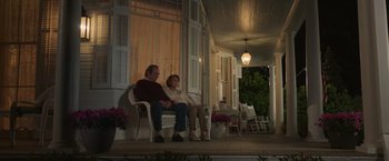 Movie still from “The Burial” (2023), directed by Maggie Betts – A man and a woman sitting on a white chair; Wide shot, Low angle