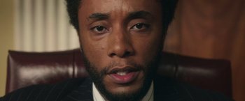 Movie still from “The Burial” (2023), directed by Maggie Betts – A person wearing a suit and tie; Close Up shot, Low angle