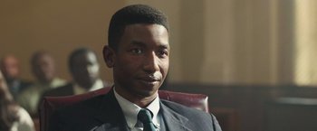 Movie still from “The Burial” (2023), directed by Maggie Betts – A person wearing a suit and tie; Close Up shot, Low angle