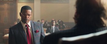 Movie still from “The Burial” (2023), directed by Maggie Betts – A man wearing a suit and tie in a courtroom; Medium shot, Over the shoulder angle