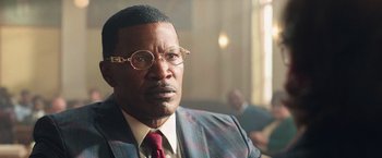 Movie still from “The Burial” (2023), directed by Maggie Betts – A person wearing a suit and tie; Close Up shot, Over the shoulder angle