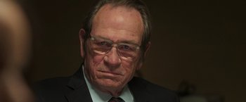 Movie still from “The Burial” (2023), directed by Maggie Betts – An older man wearing glasses and a suit; Close Up shot, Over the shoulder angle