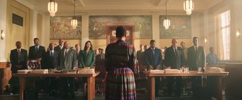 Movie still from “The Burial” (2023), directed by Maggie Betts – A group of people standing in front of a judge; Extreme Wide shot, Low angle