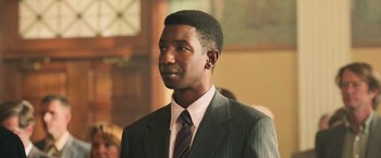 Movie still from “The Burial” (2023), directed by Maggie Betts – A man in a suit and tie looking to his left; Close Up shot, Low angle