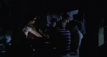 A group of young men sitting around a dark room