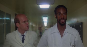 Movie still from “The Burning” (1981), directed by Tony Maylam – A man in a white dress shirt and tie standing next to another man in glasses; Close Up shot, Low angle